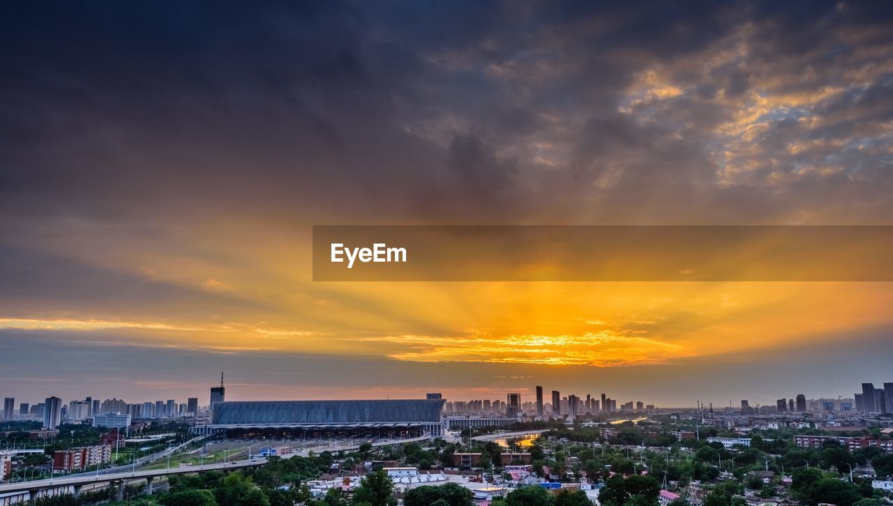 Panoramic view of city against cloudy sky during sunset