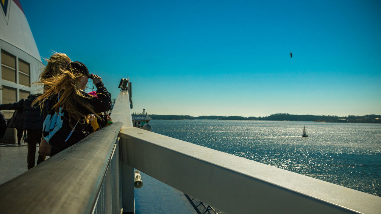 REAR VIEW OF PEOPLE PHOTOGRAPHING AT SEA