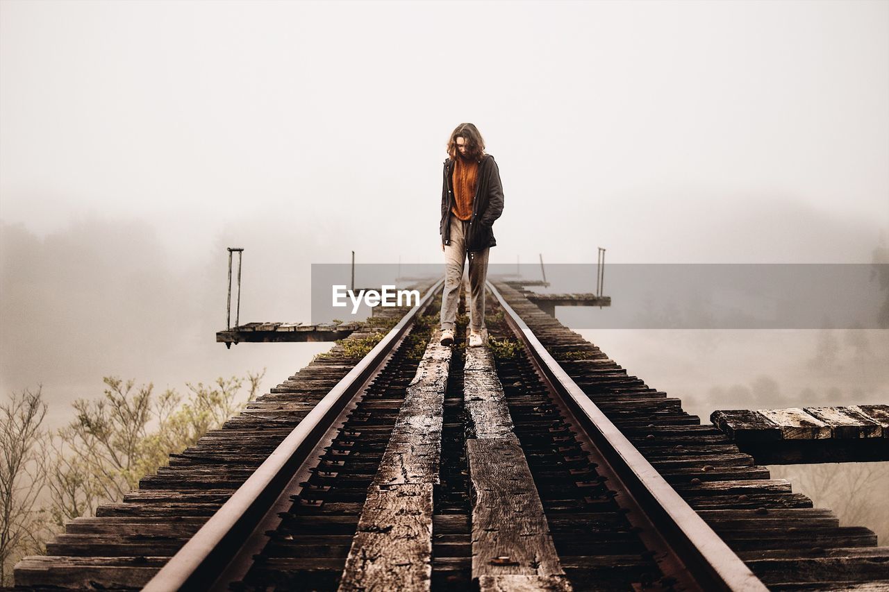 WOMAN STANDING ON RAILROAD TRACKS