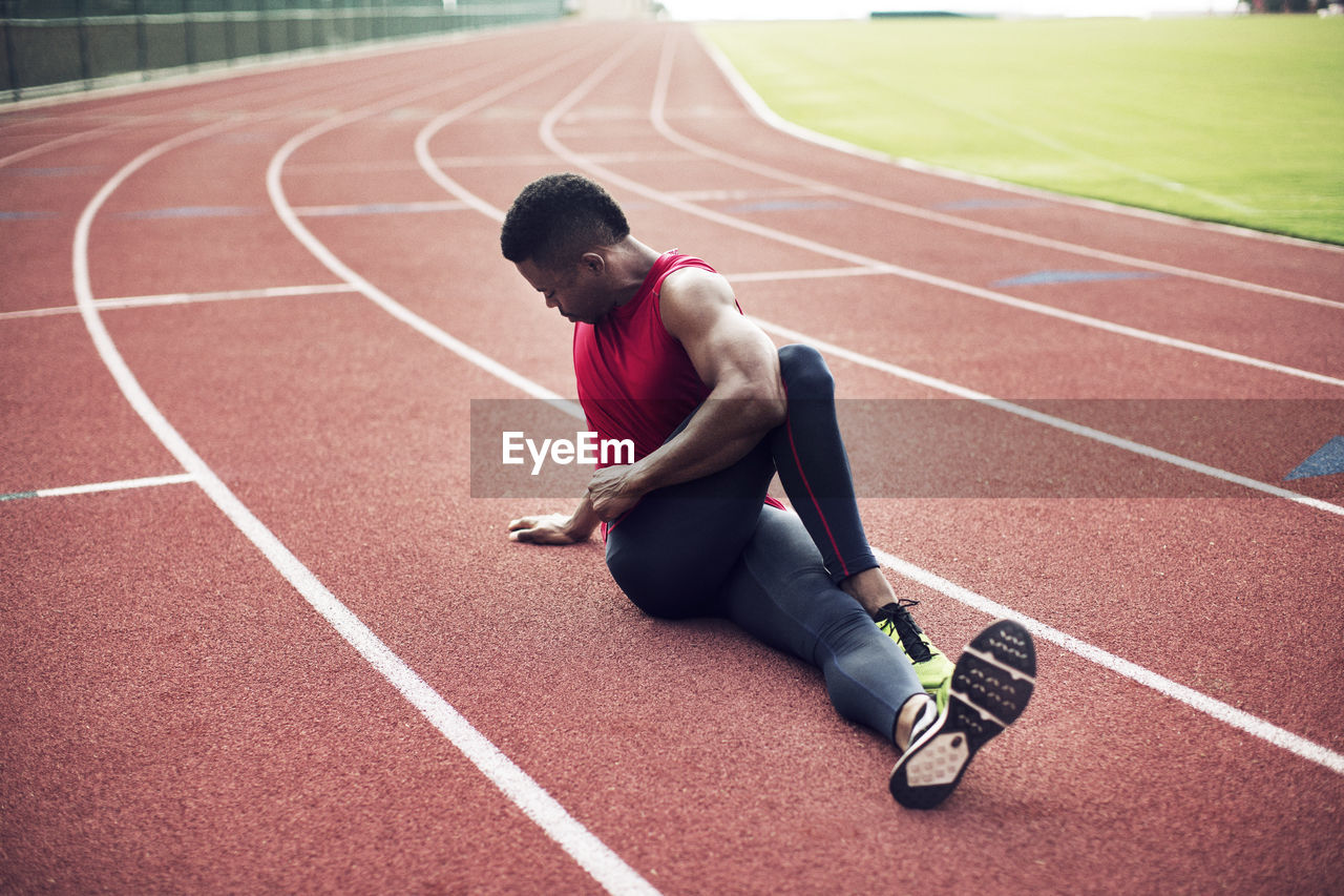 Full length of male athlete exercising on running tracks