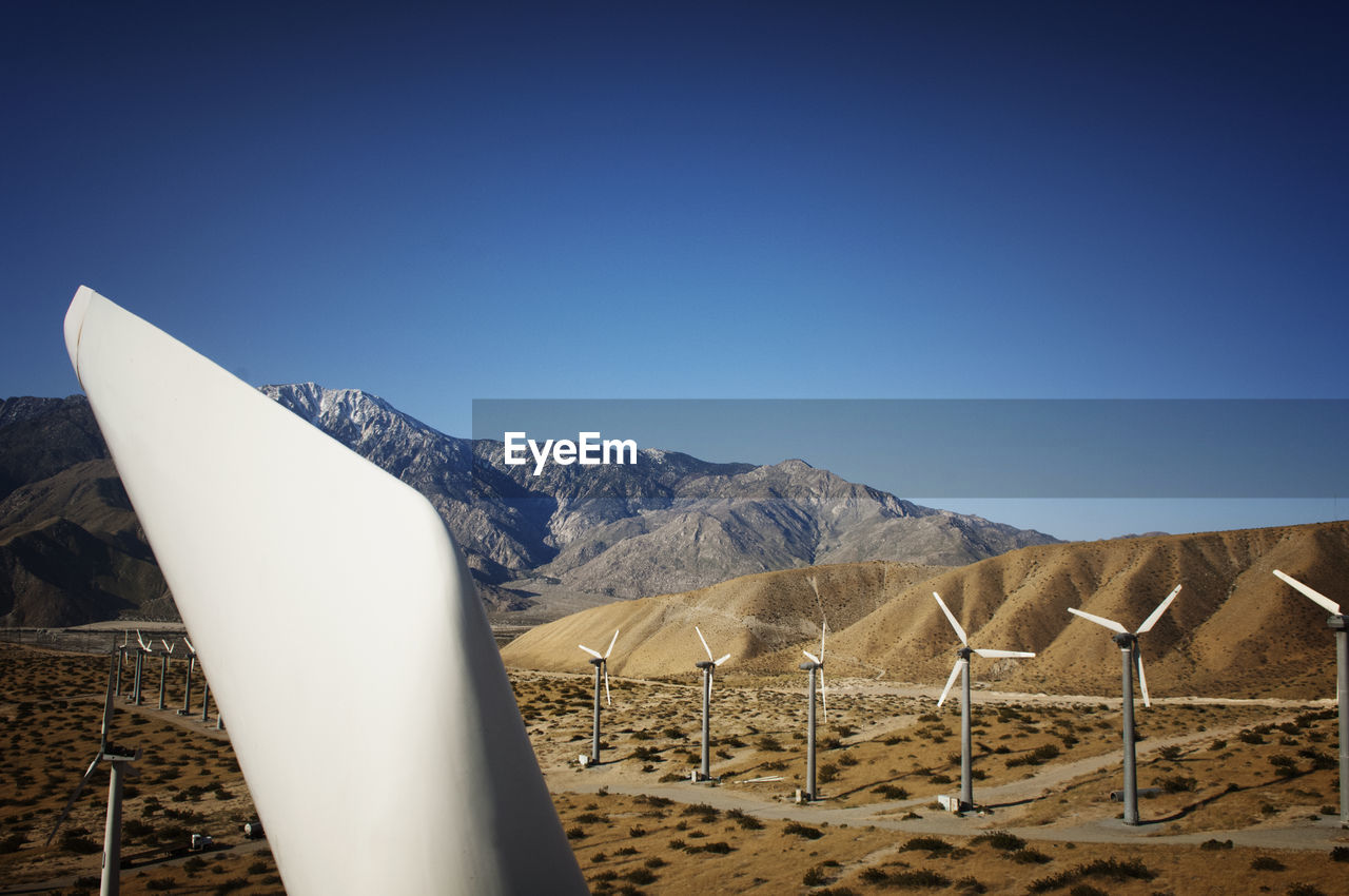 Wind turbines on field against clear blue sky