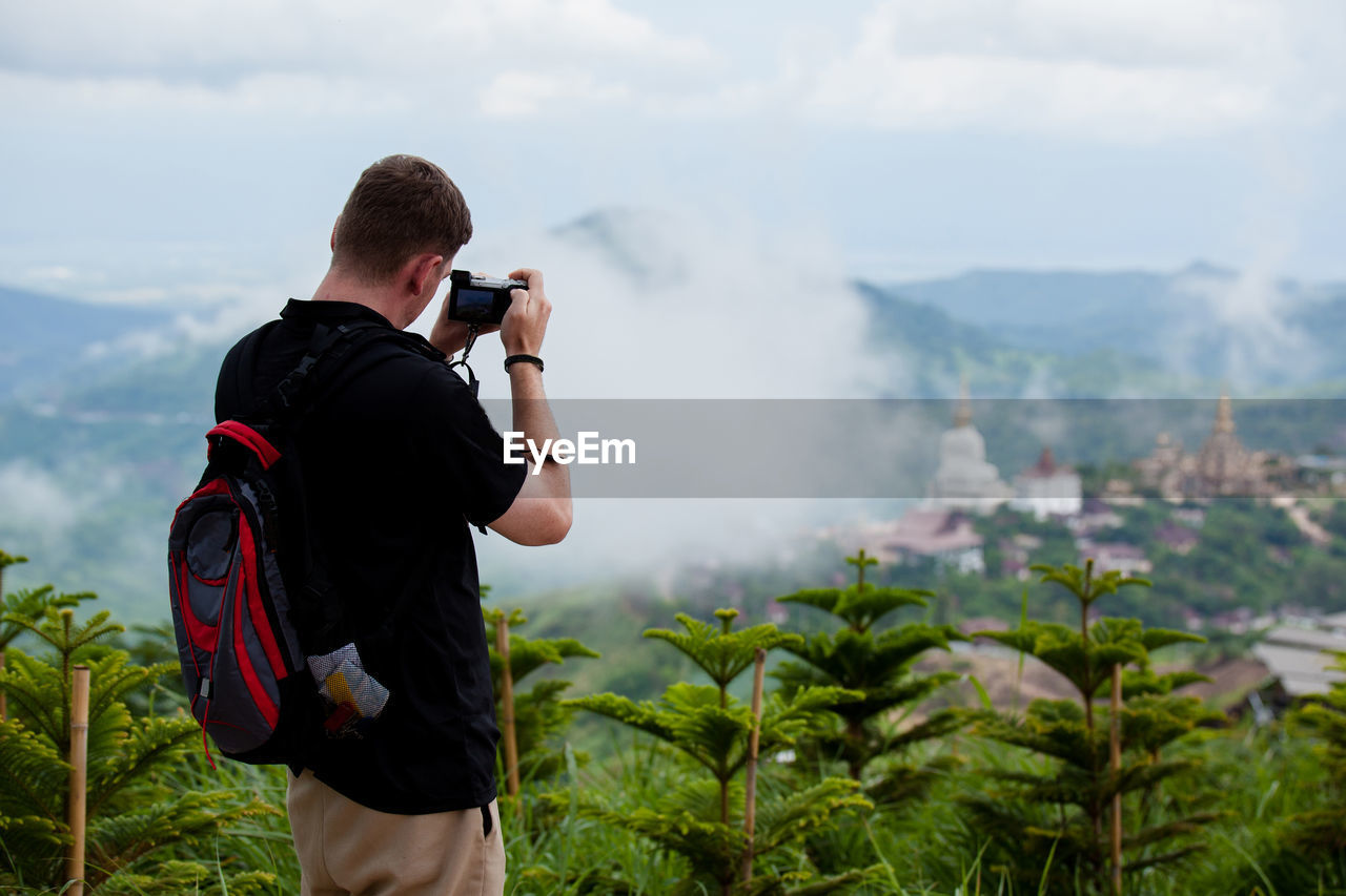 Rear view of man photographing while standing on mountain