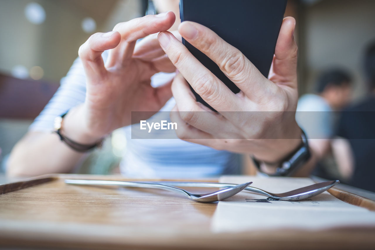 Midsection of person using mobile phone at table