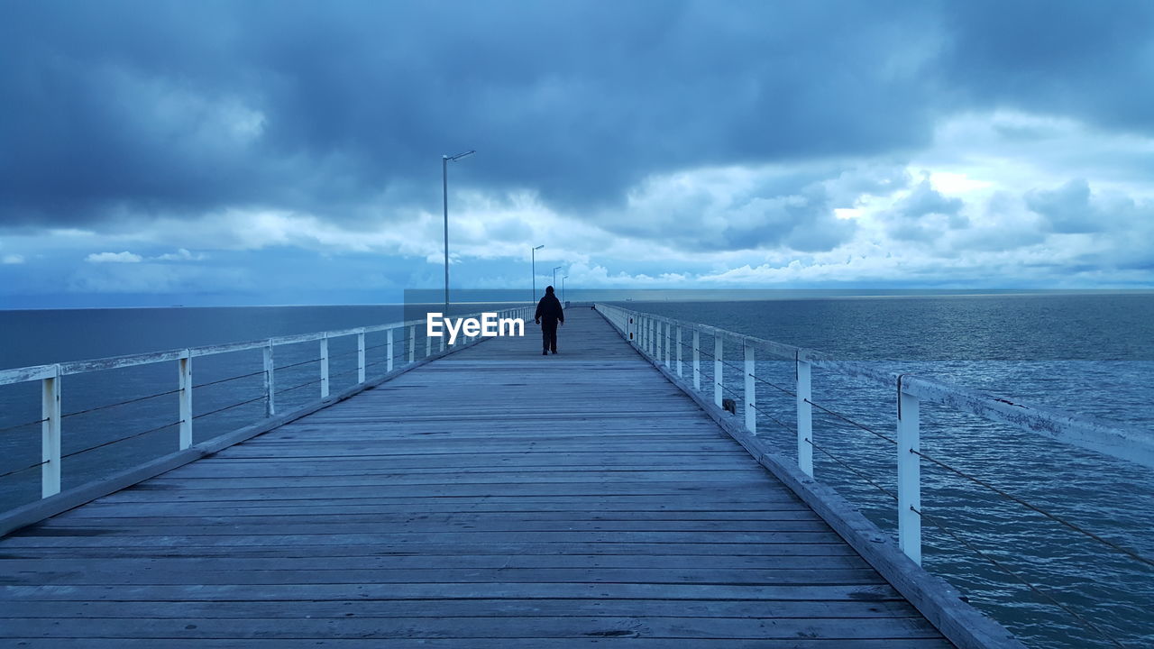 Rear view of man on jetty against sea