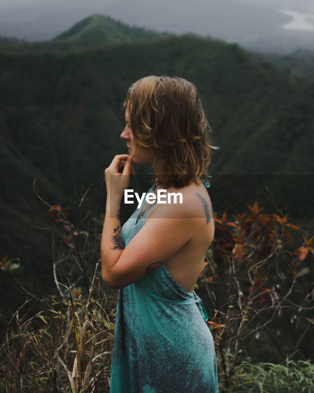 Side view of woman standing against mountain