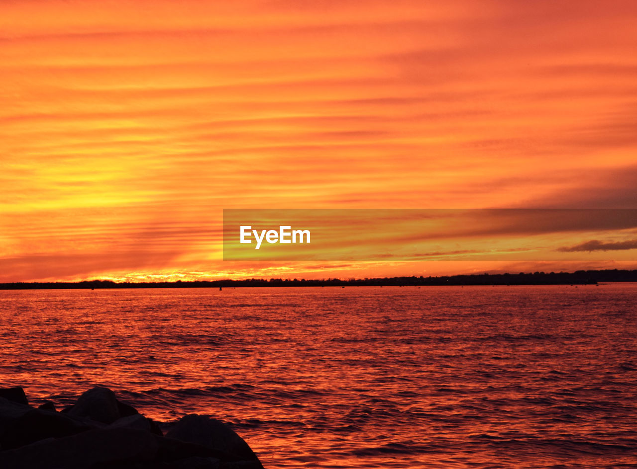 Scenic view of lake against orange cloudy sky