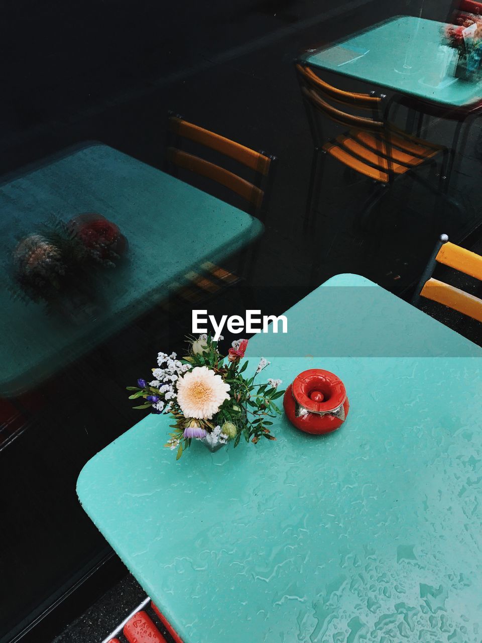 High angle view of flowers in vase on wet table at restaurant