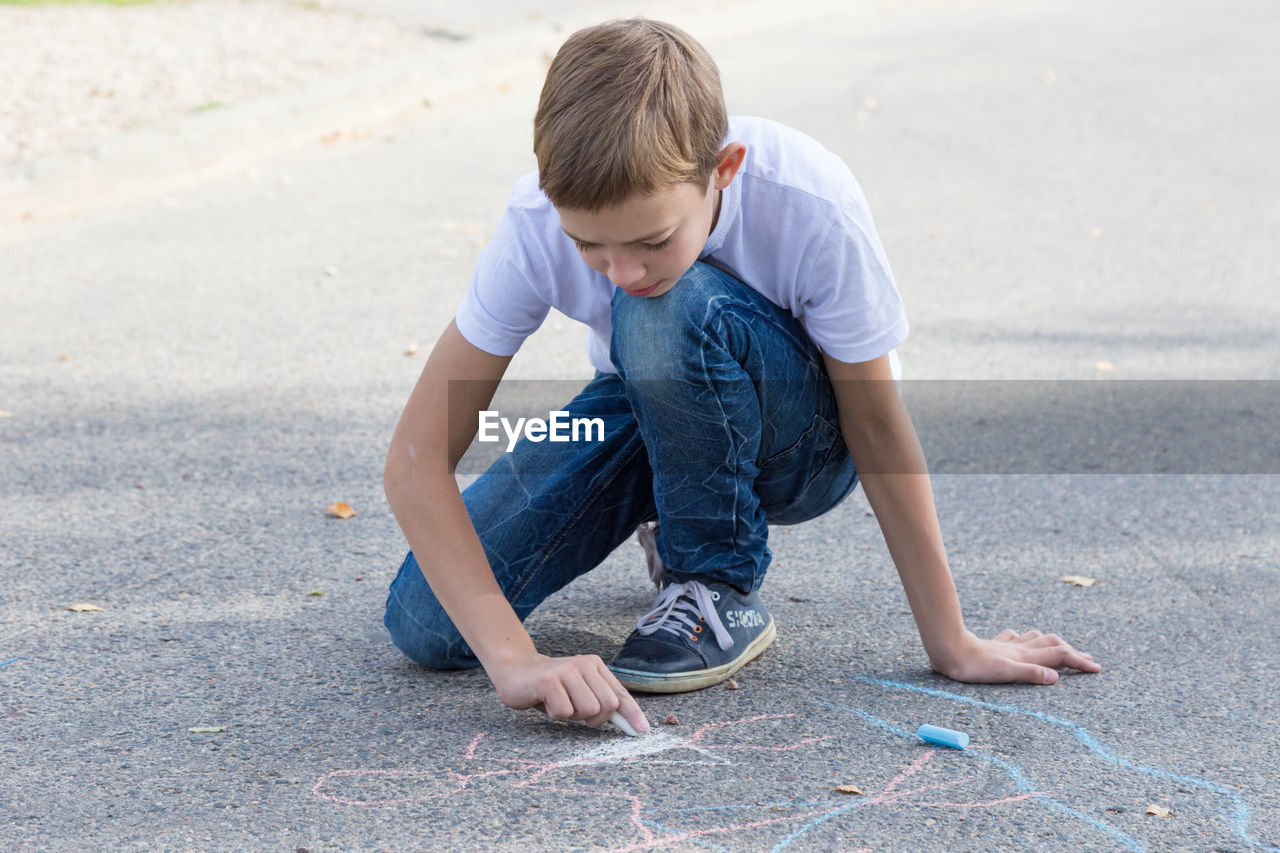 FULL LENGTH OF BOY LOOKING AT CAMERA ON ROAD