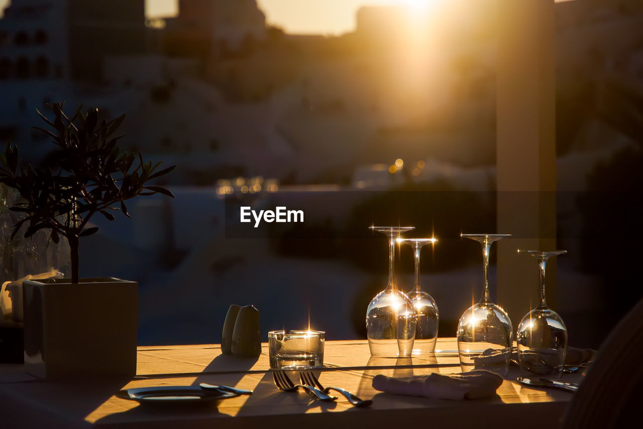 Restaurant table decorated with glasses on terrace in sunset light on the island santorini, greece