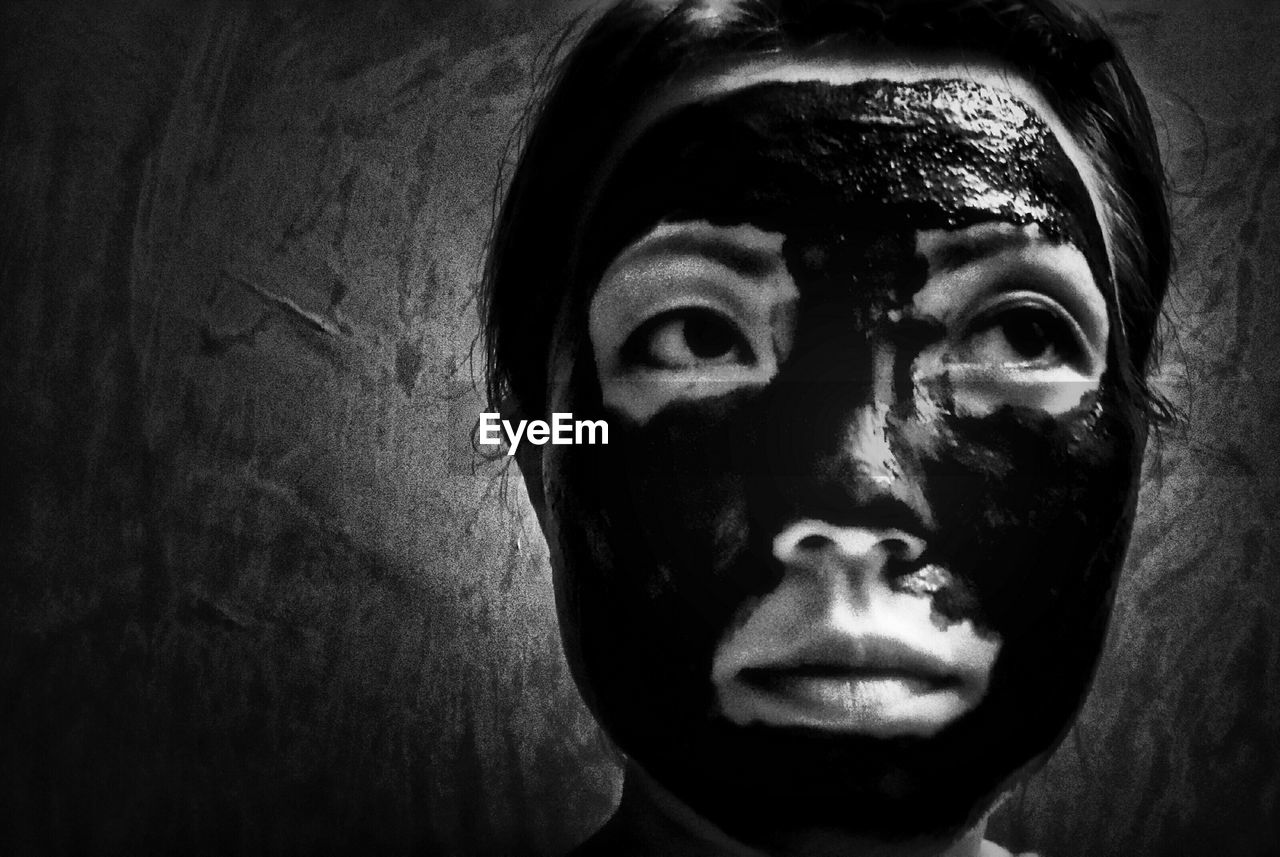 Close-up of young woman with facial mask against wall