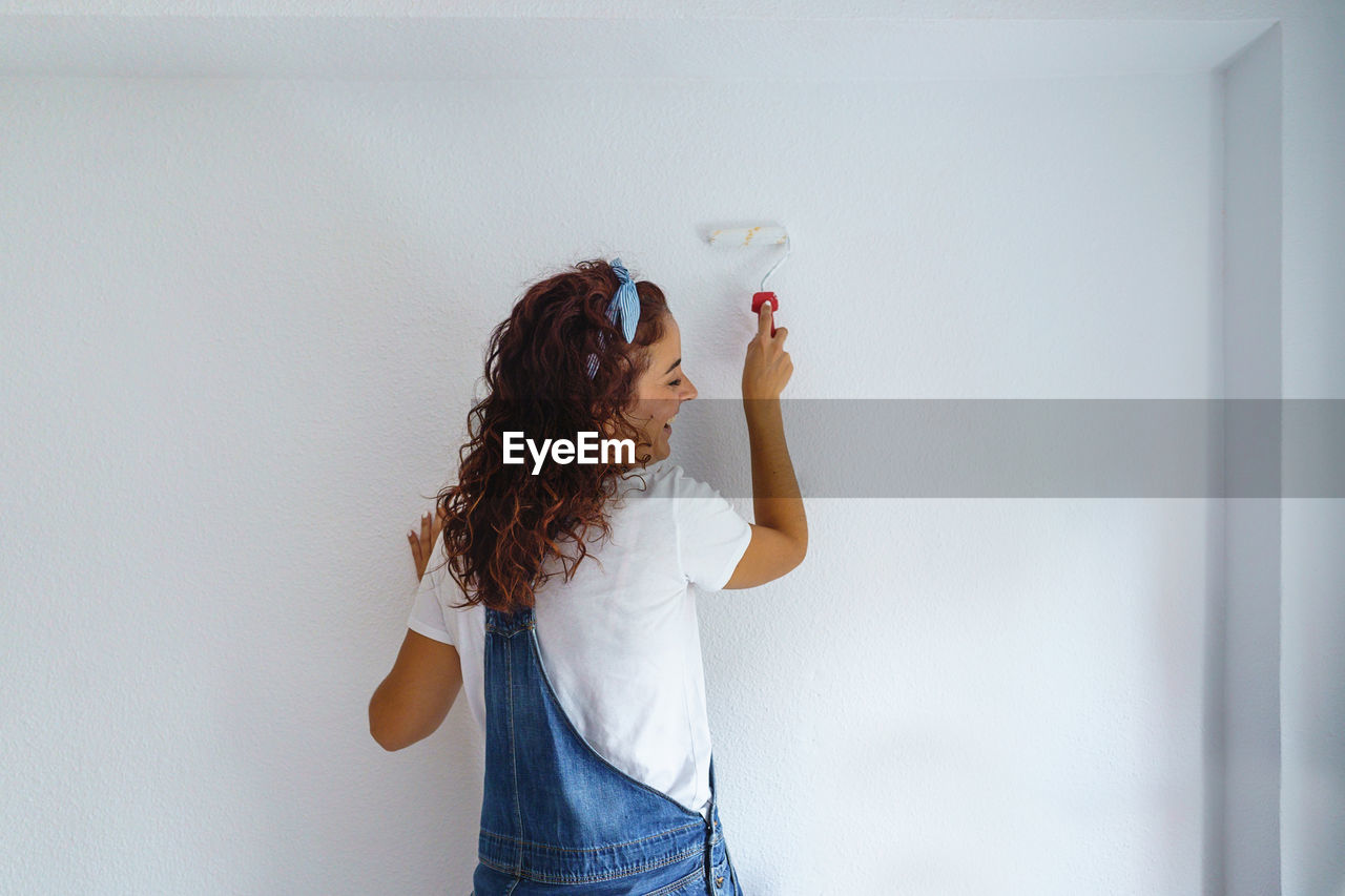 Rear view of woman painting wall at home