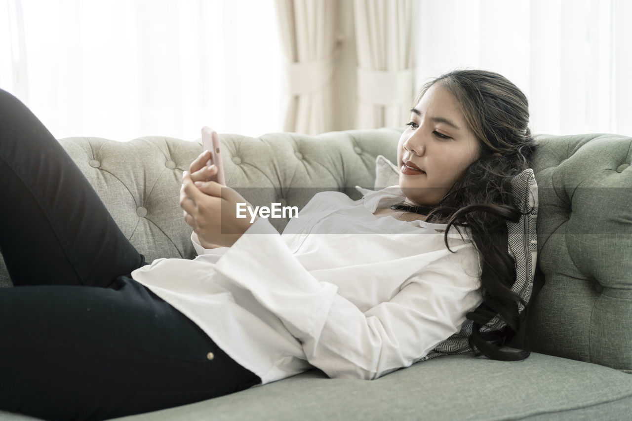 WOMAN LYING ON SOFA AT HOME