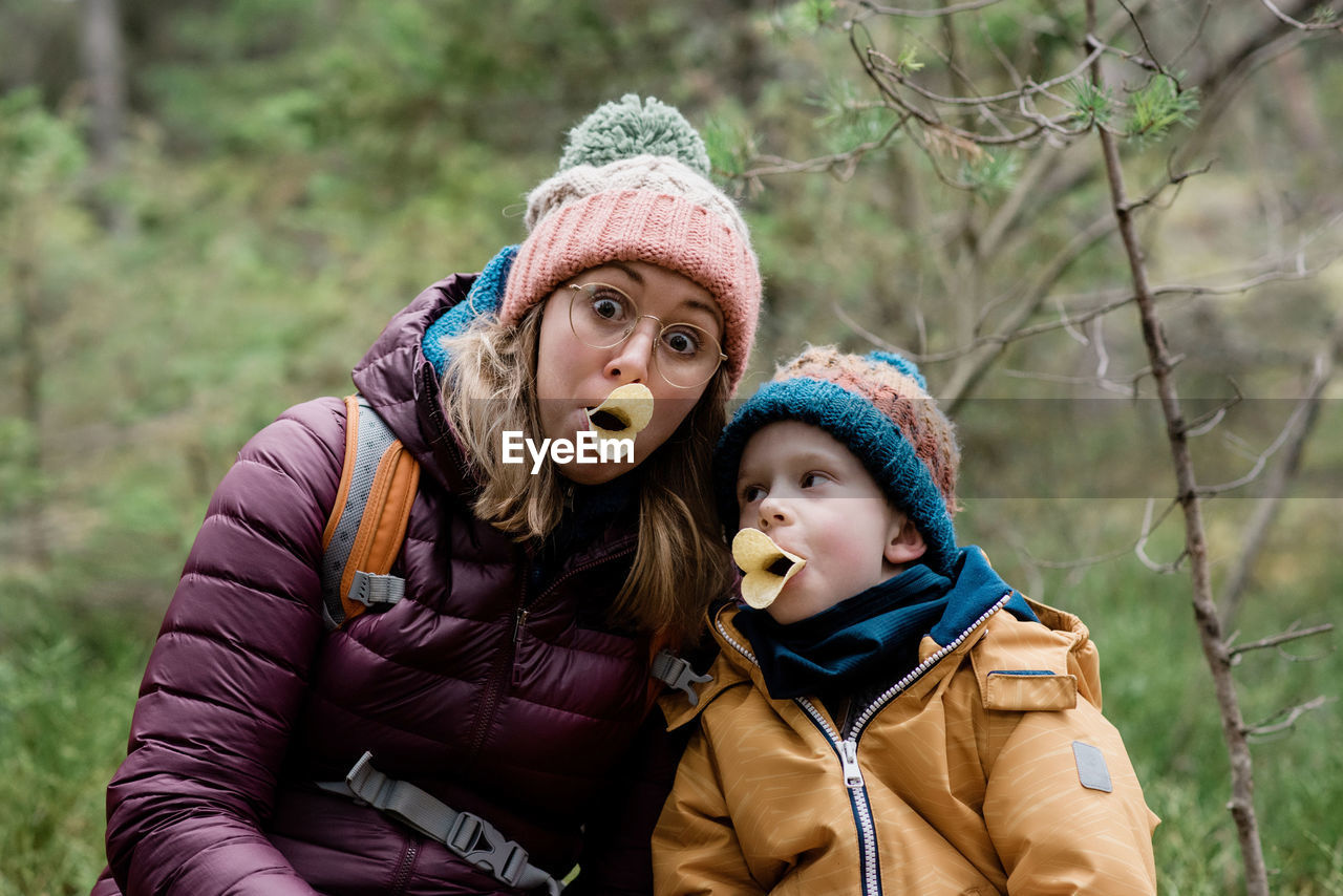 Mom and son making silly faces with food whilst hiking in winter