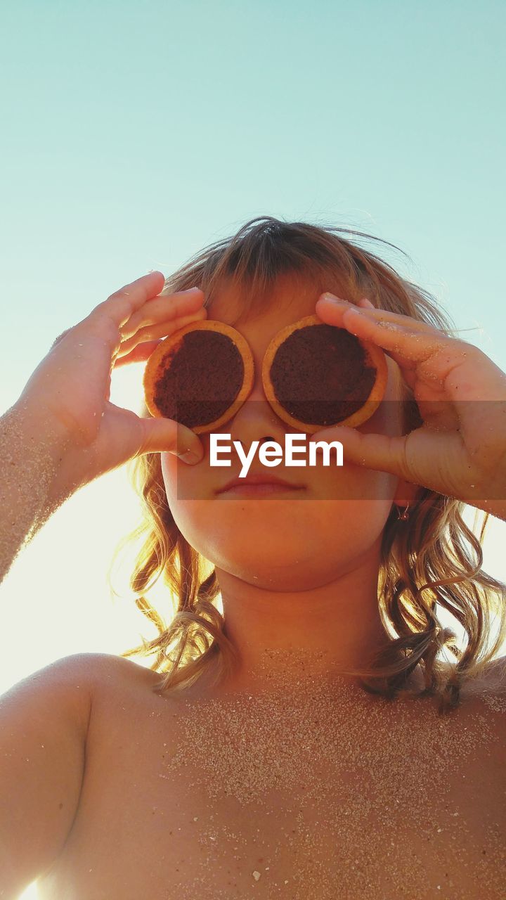 A girl on the beach creates fachion glasses from round chocolate chip cookie.