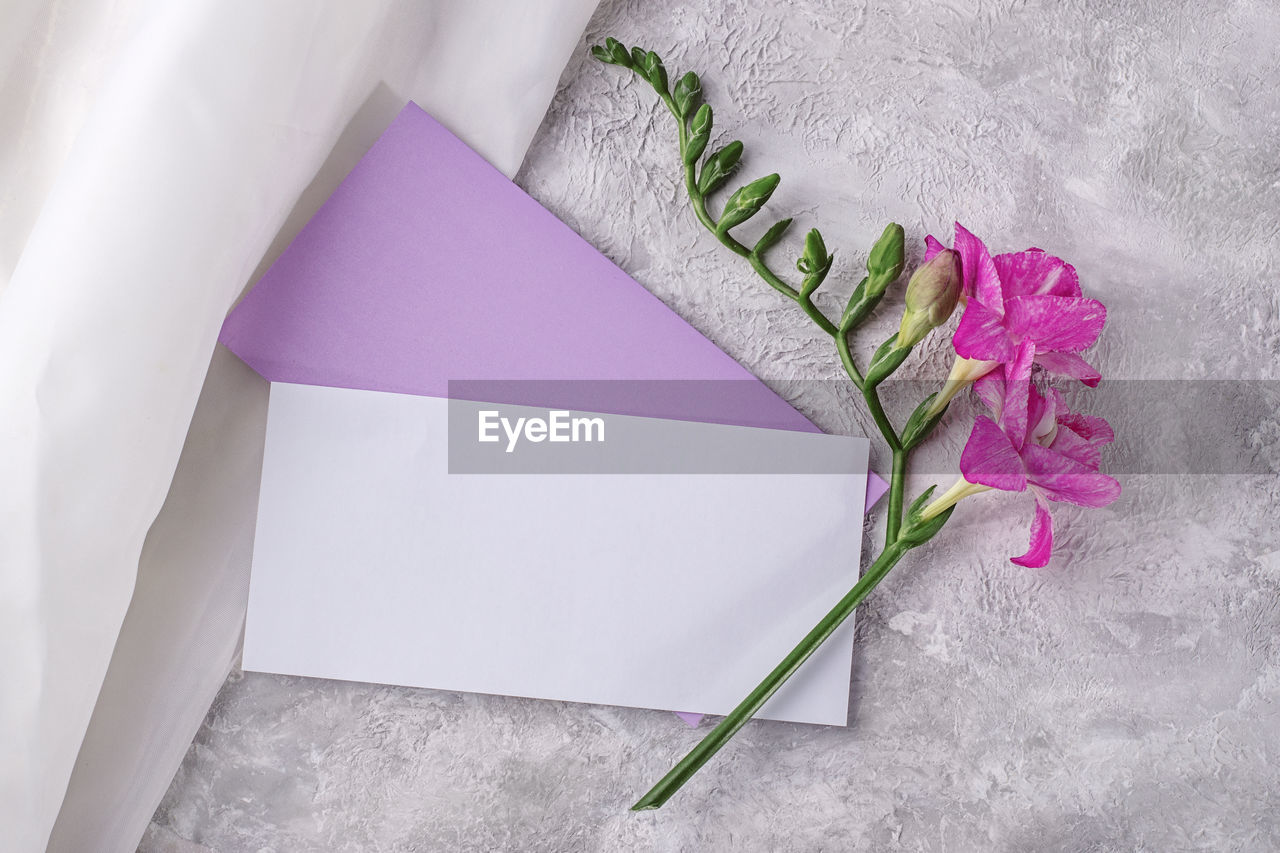 Invitation card mockup in veri pery envelope with freesia flower.