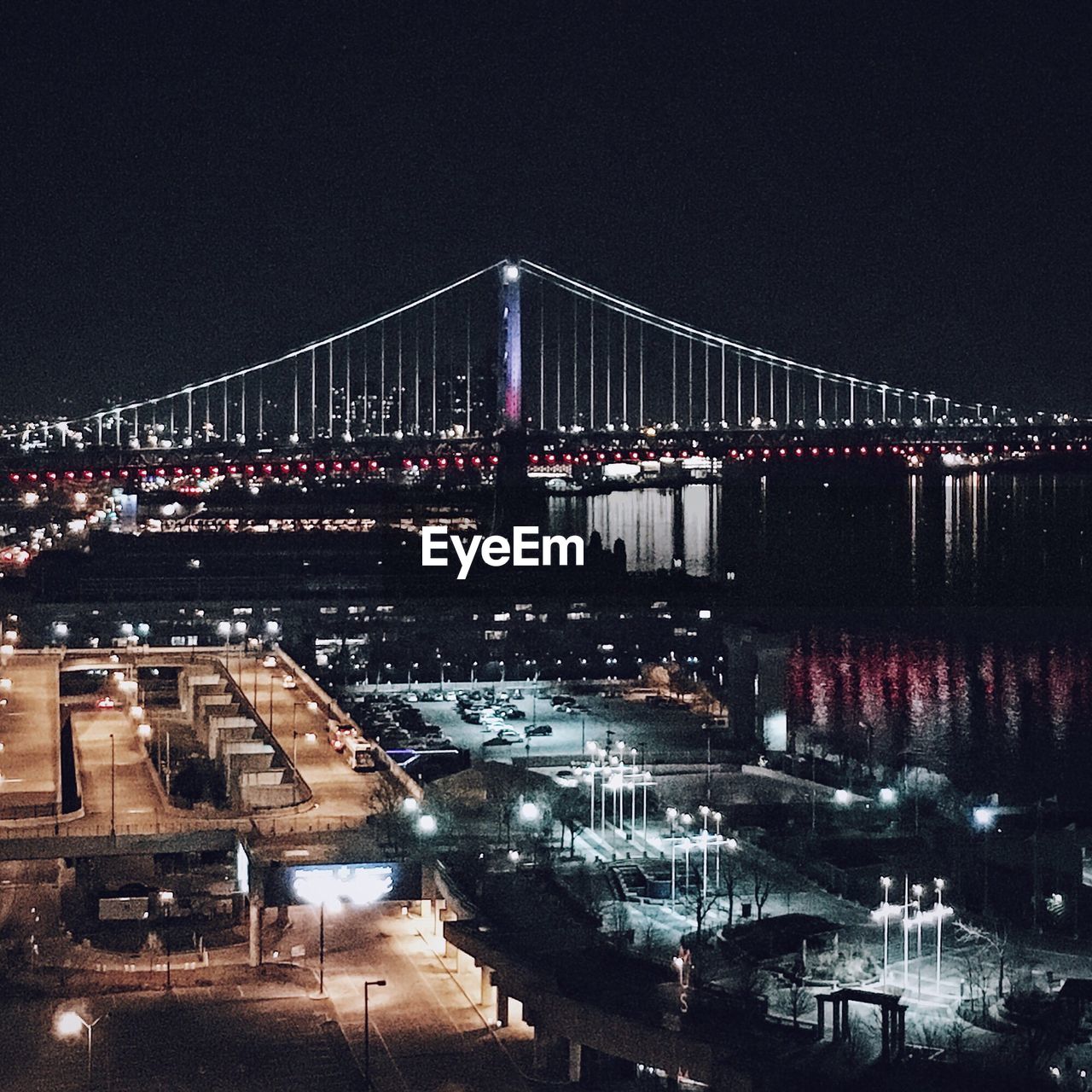 ILLUMINATED BRIDGE OVER RIVER AT NIGHT