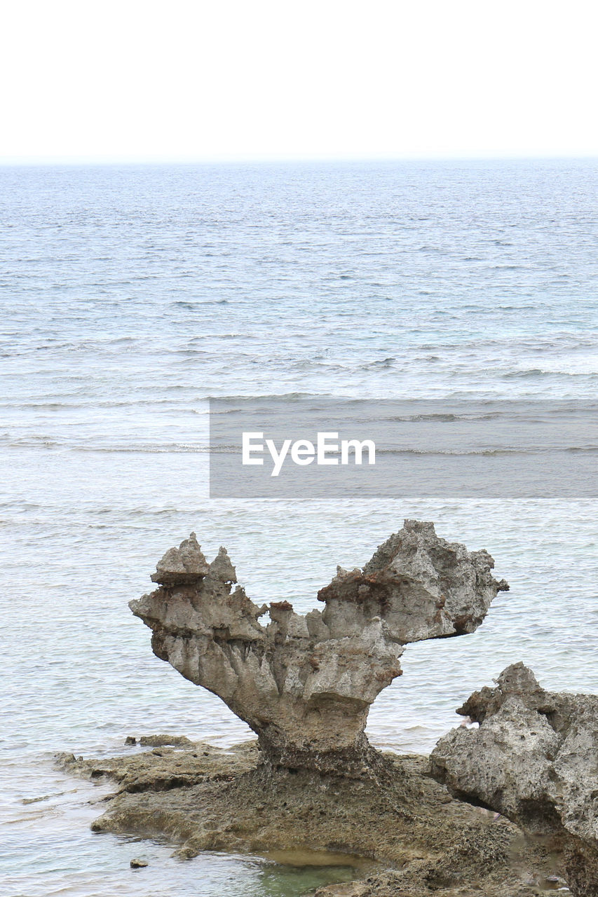 ROCKS ON SHORE AGAINST CLEAR SKY