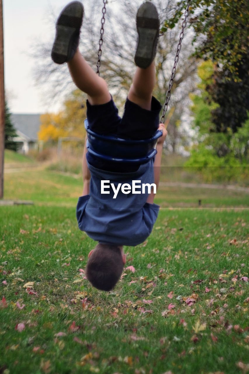 Playful boy on swing at park