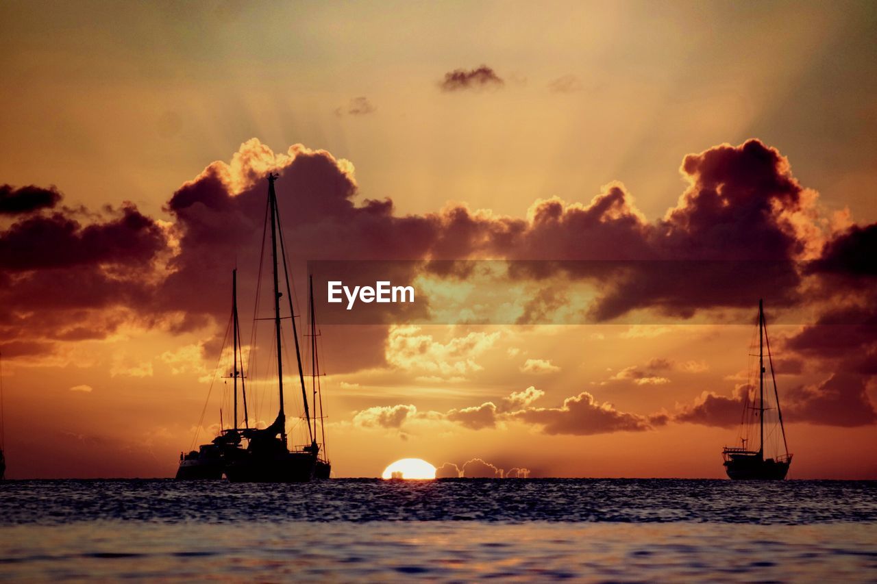 Silhouette of sailboat in sea during sunset