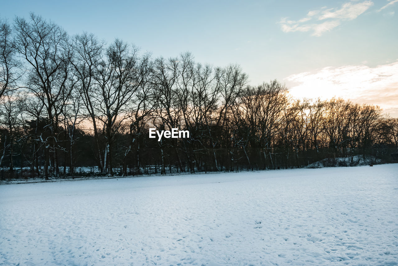 SNOW COVERED FIELD AGAINST SKY DURING SUNSET