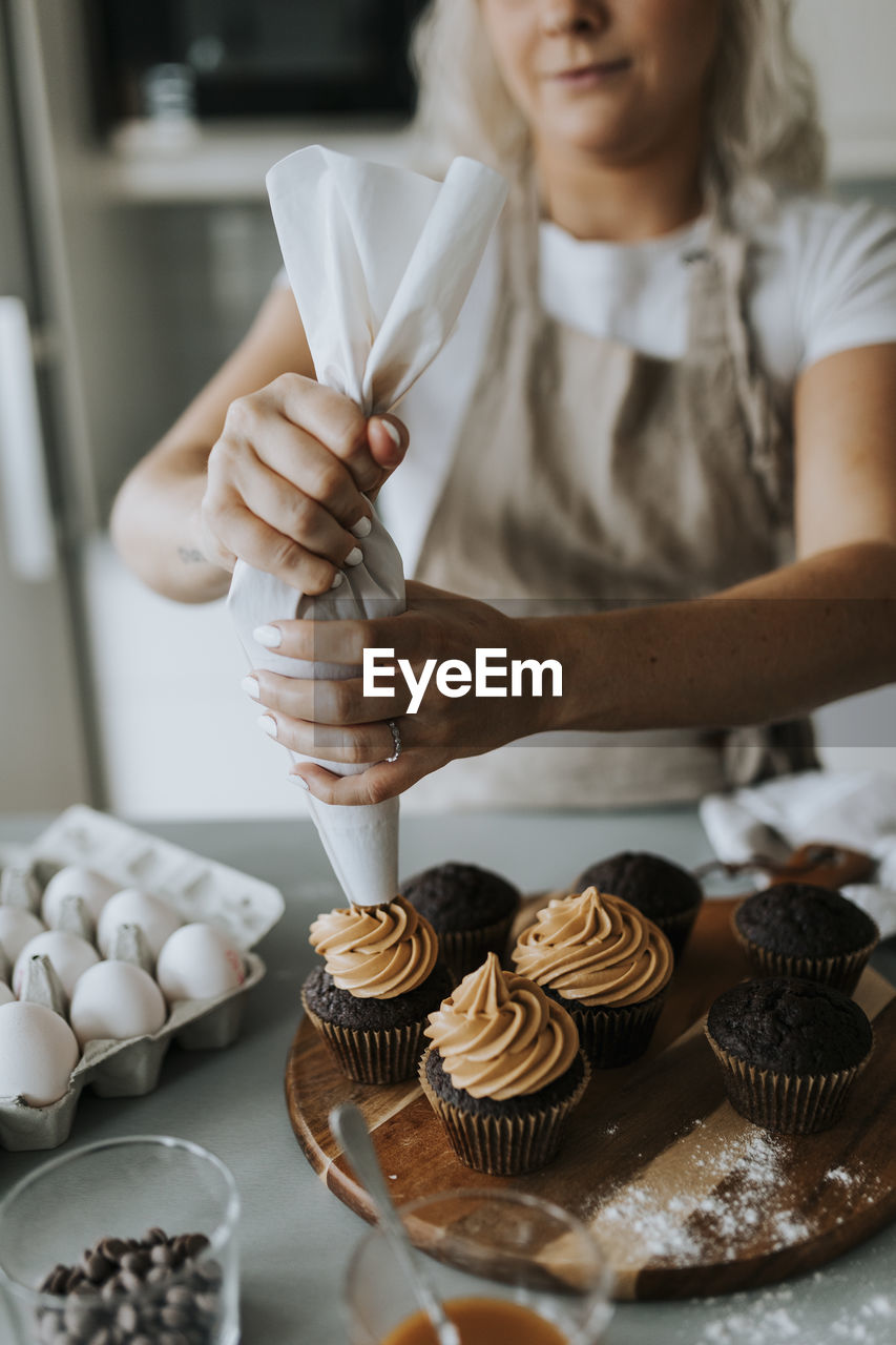 Woman putting icing on cupcakes