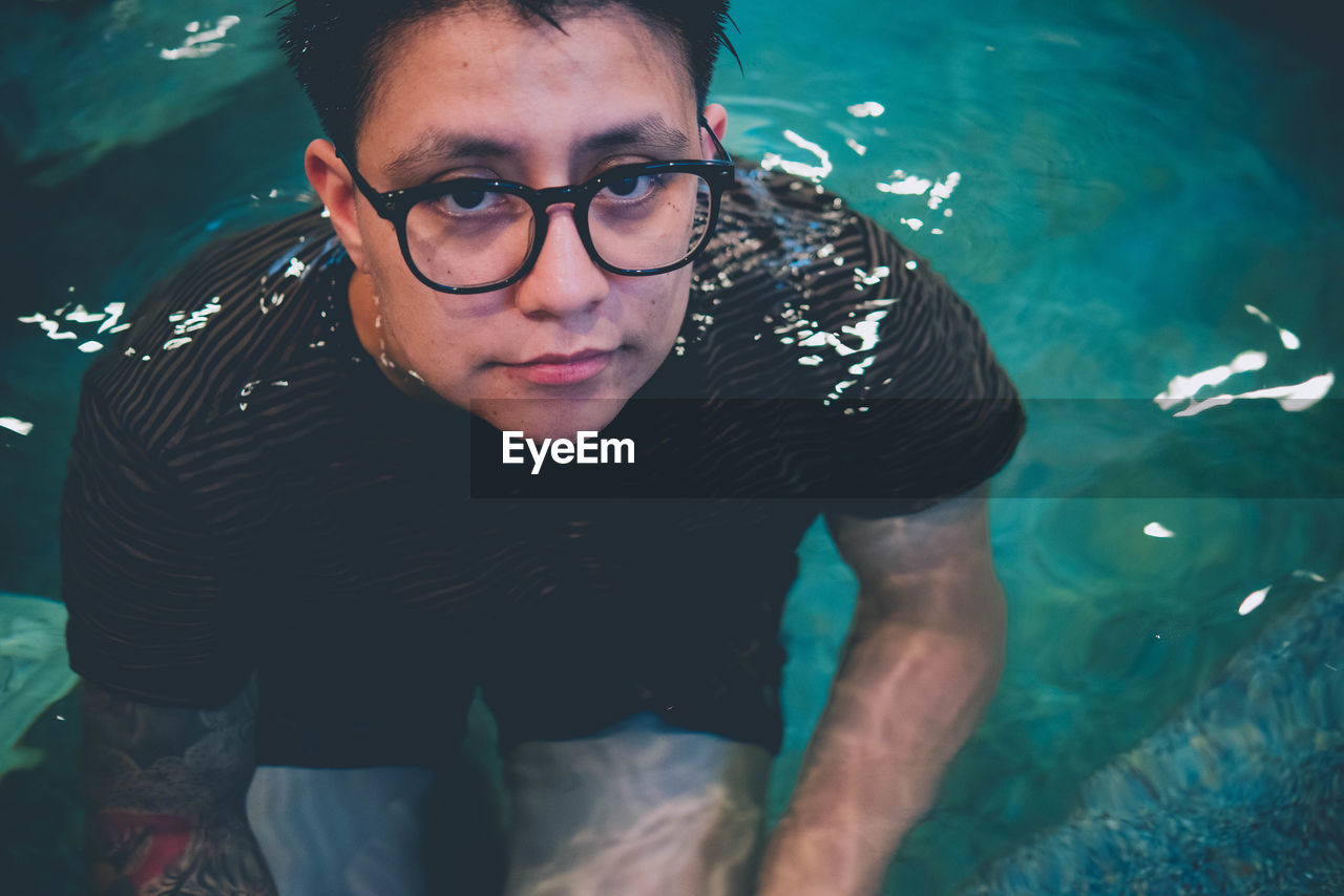 Portrait of woman wearing eyeglasses swimming in pool