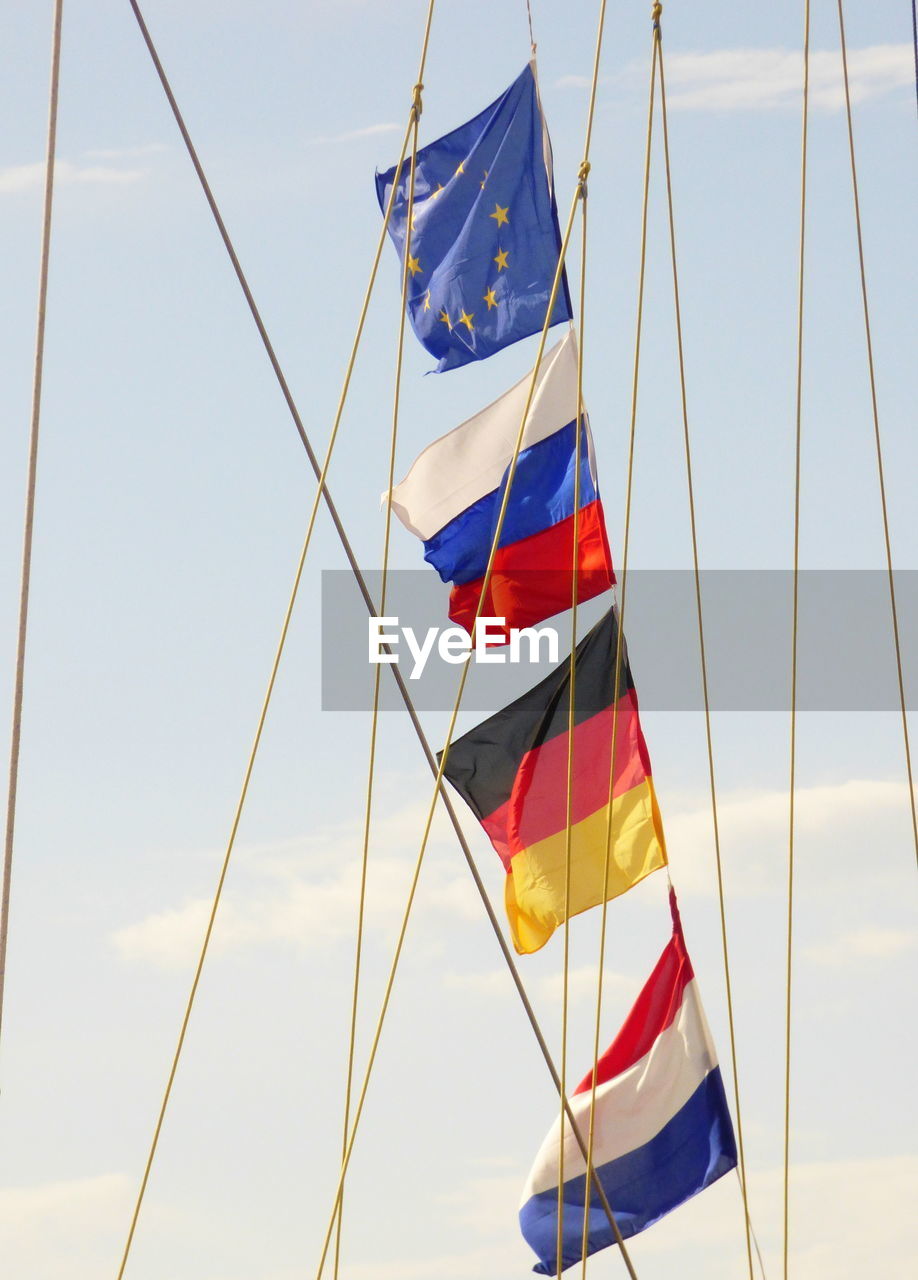 Low angle view of national flags on rope against sky