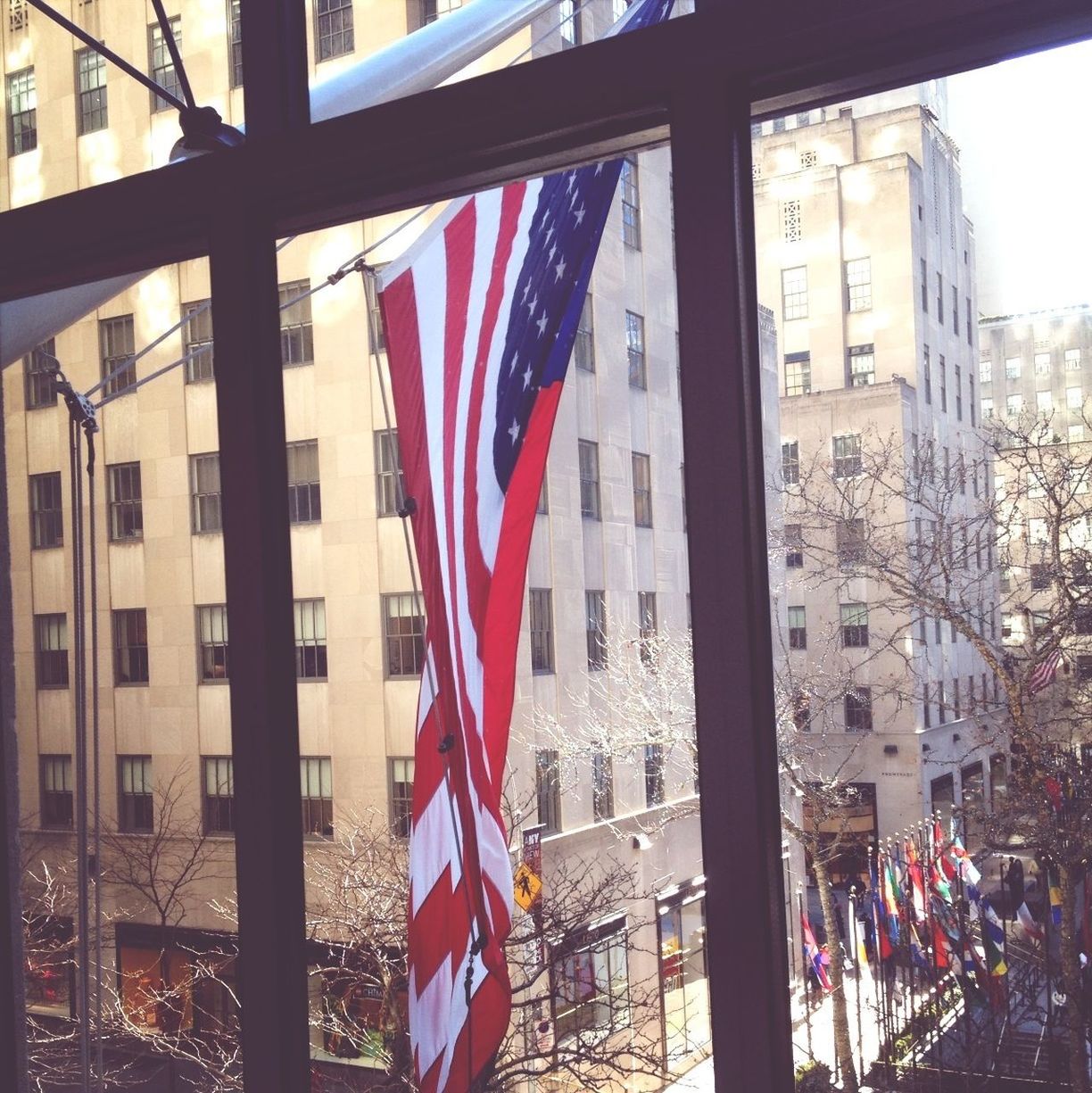 View of buildings and american flag through window