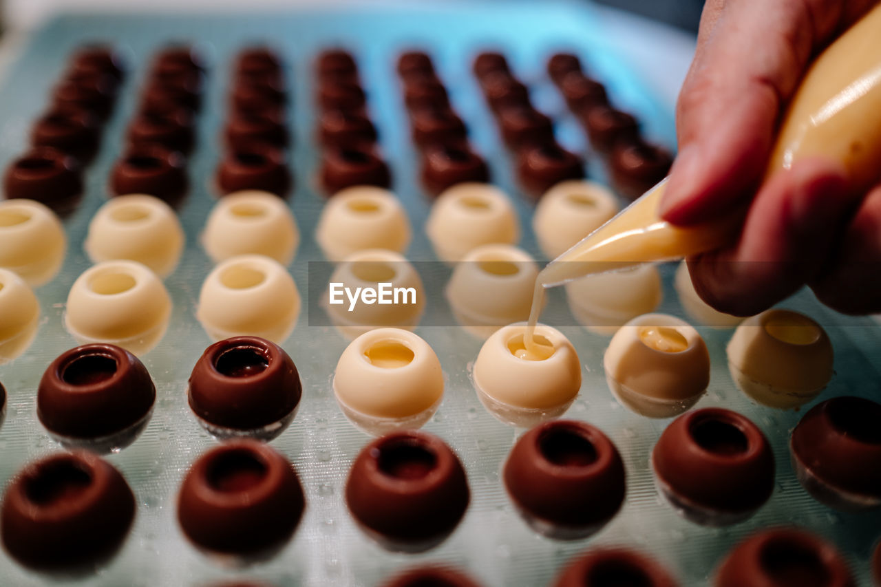 Hand filling pralines with chocolate