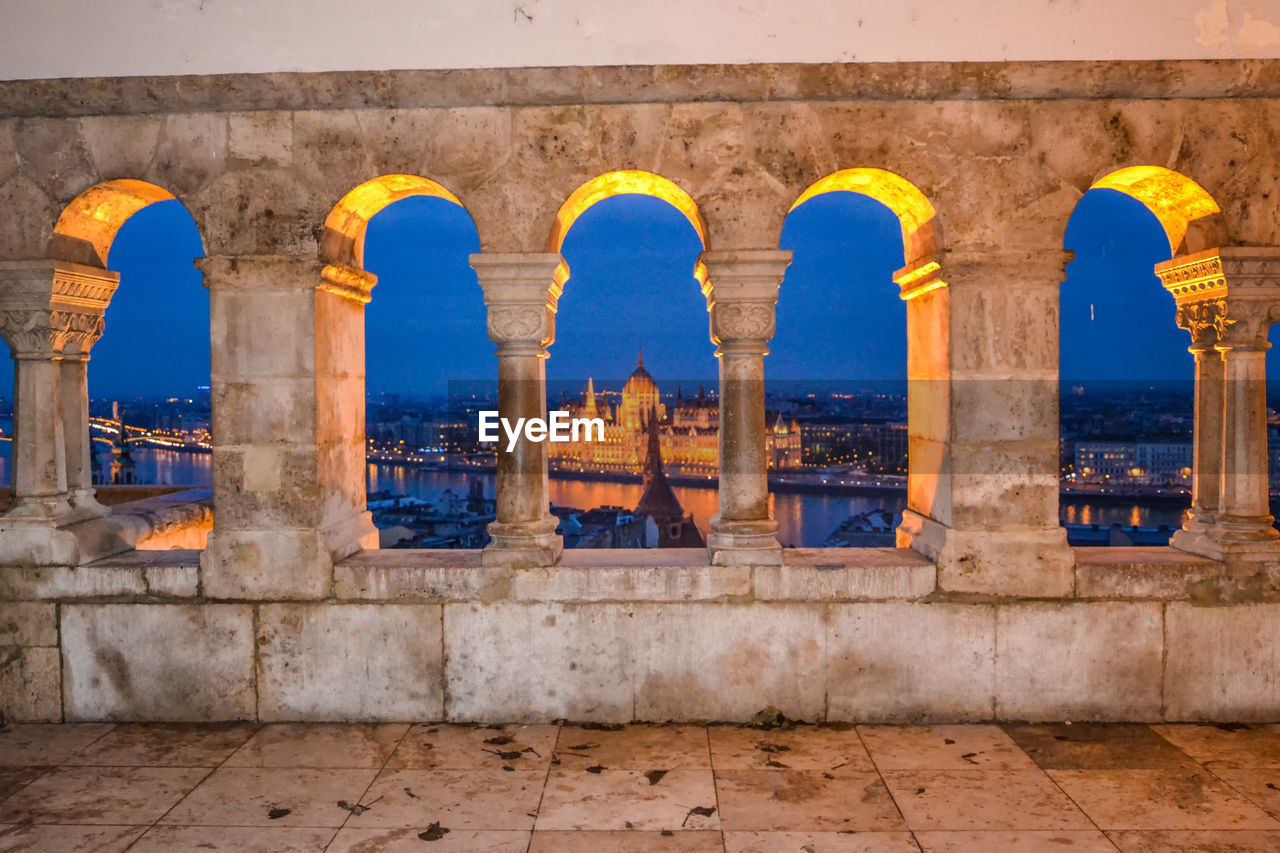 Budapest parliament building seen through arches at night