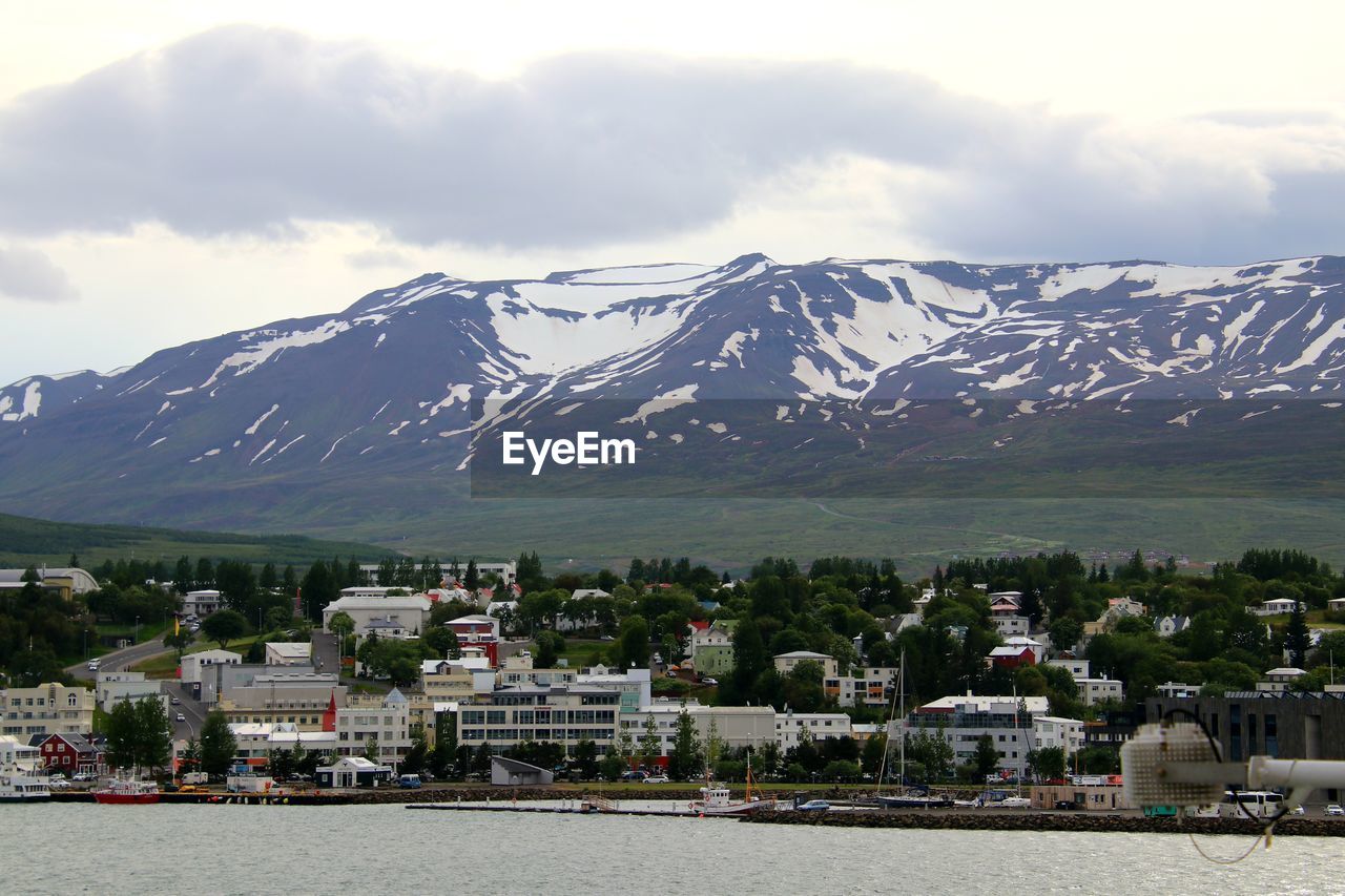 Scenic view of townscape by mountains against sky