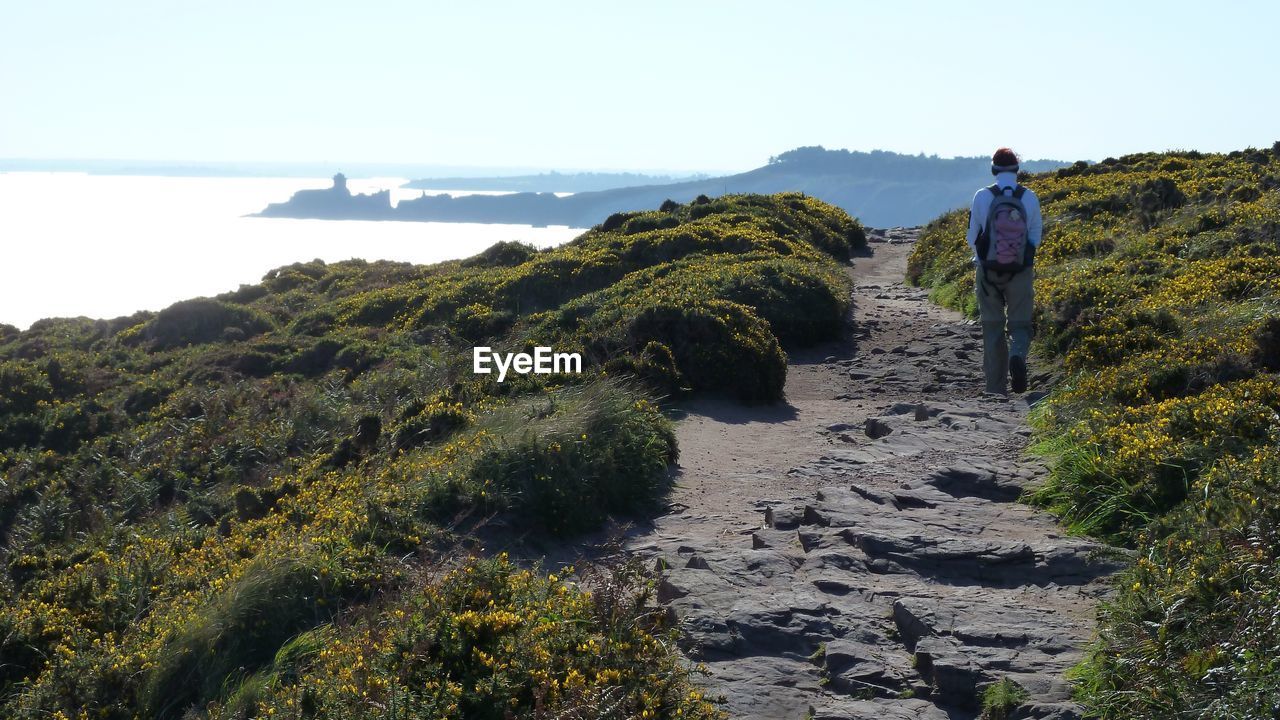 REAR VIEW OF MAN WALKING ON ROCK