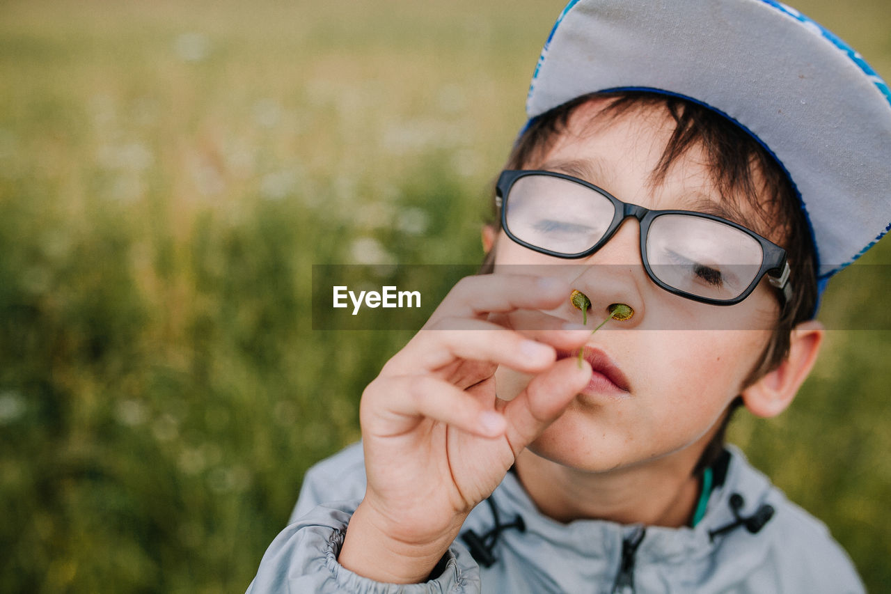 Close-up of boy putting flower into nose outdoors