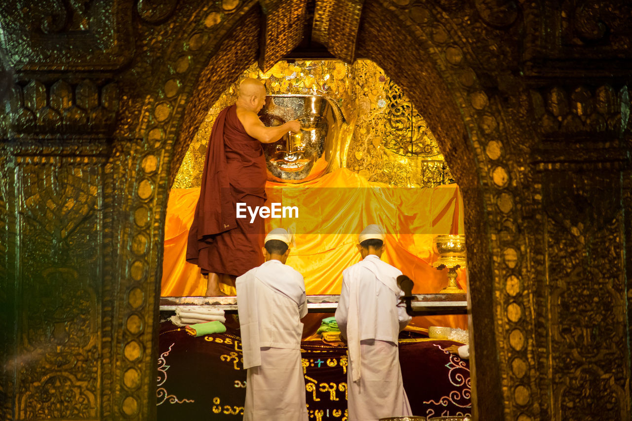 REAR VIEW OF MAN STANDING AT TEMPLE