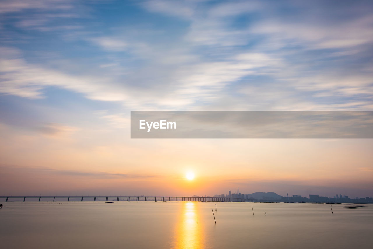 sky, water, sunset, beauty in nature, cloud, scenics - nature, tranquility, nature, tranquil scene, reflection, sea, idyllic, sun, sunlight, no people, dramatic sky, horizon, dawn, outdoors, horizon over water, environment, beach, orange color, land, landscape, afterglow, travel destinations, non-urban scene, silhouette, travel, evening