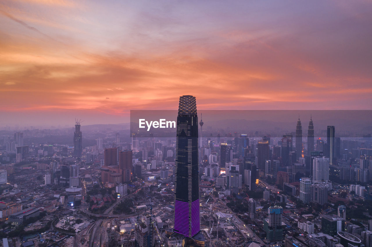 Aerial view of modern buildings in city against sky during sunset