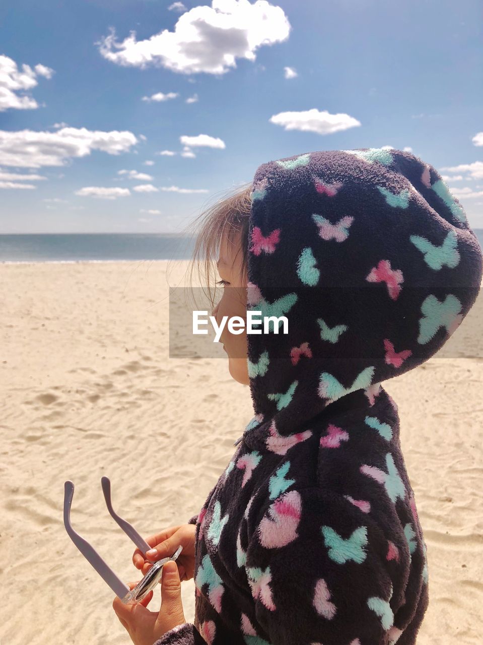 Close-up of girl wearing hooded shirt at beach