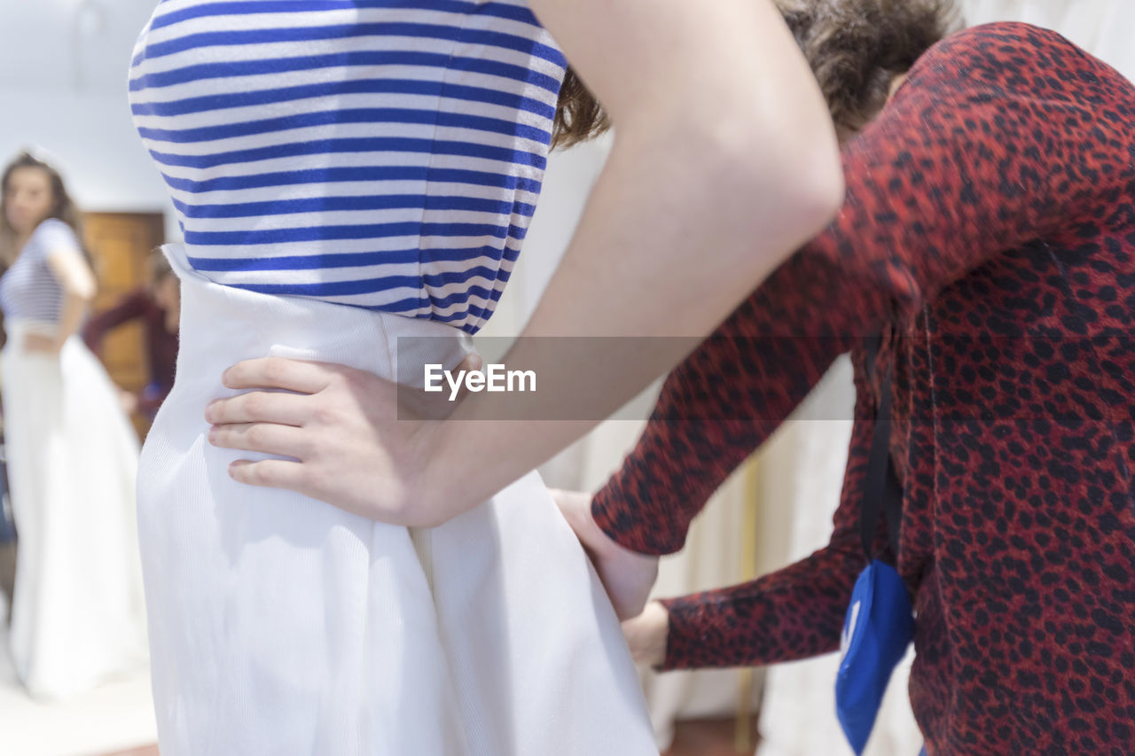 Woman assisting customer in trying dress at store