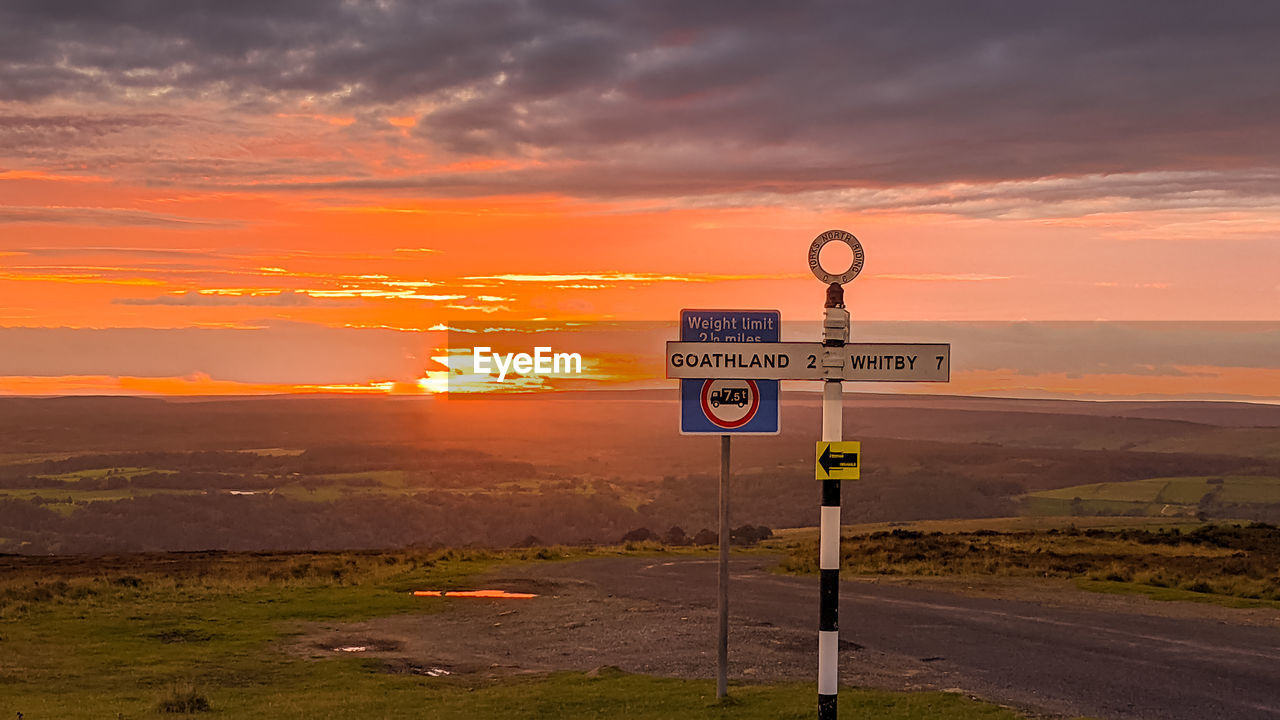 ROAD SIGN AGAINST ORANGE SKY