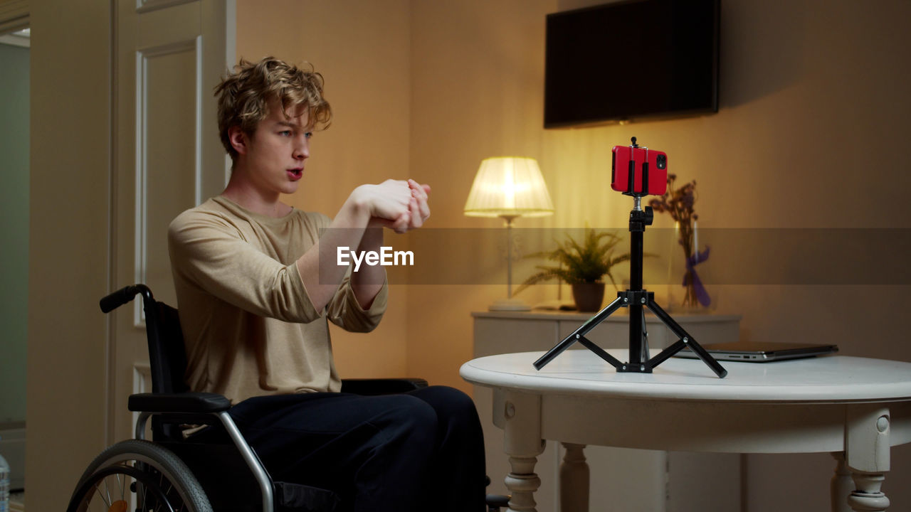 Young man exercising while vlogging at home