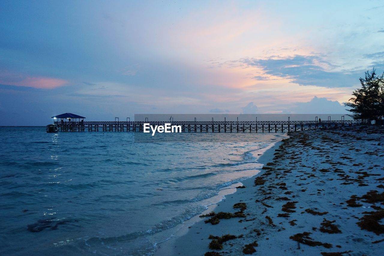 PIER OVER SEA AGAINST SKY AT SUNSET