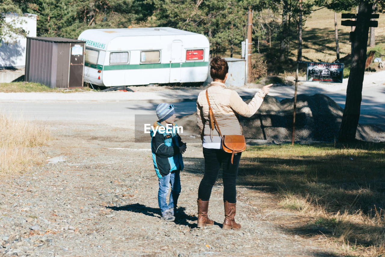 Rear view of woman with son standing on road