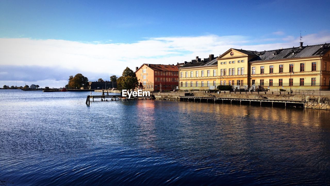 Jetty in lake by building against sky