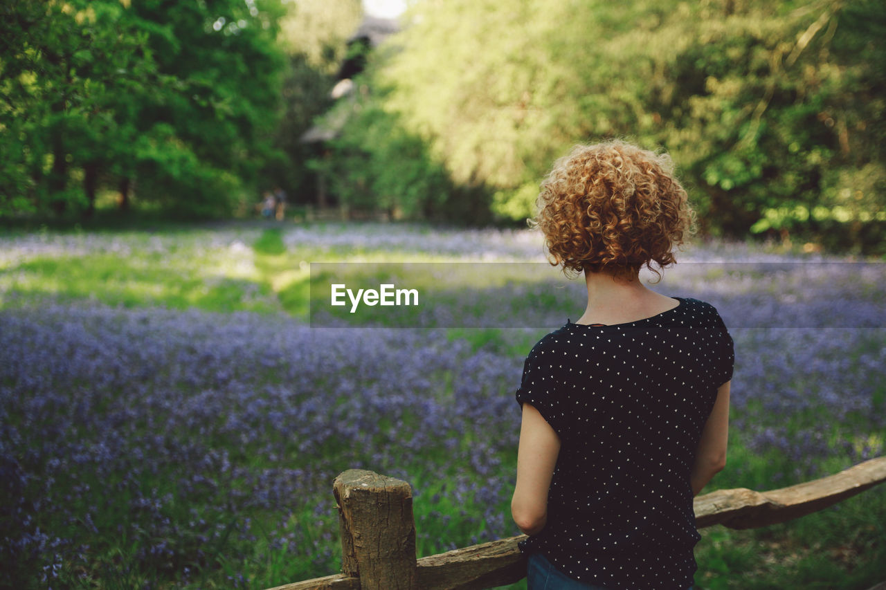 Rear view of woman standing against flowers at park