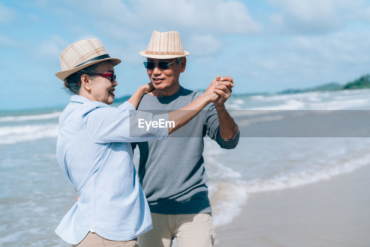 Happy couple dancing while standing at beach