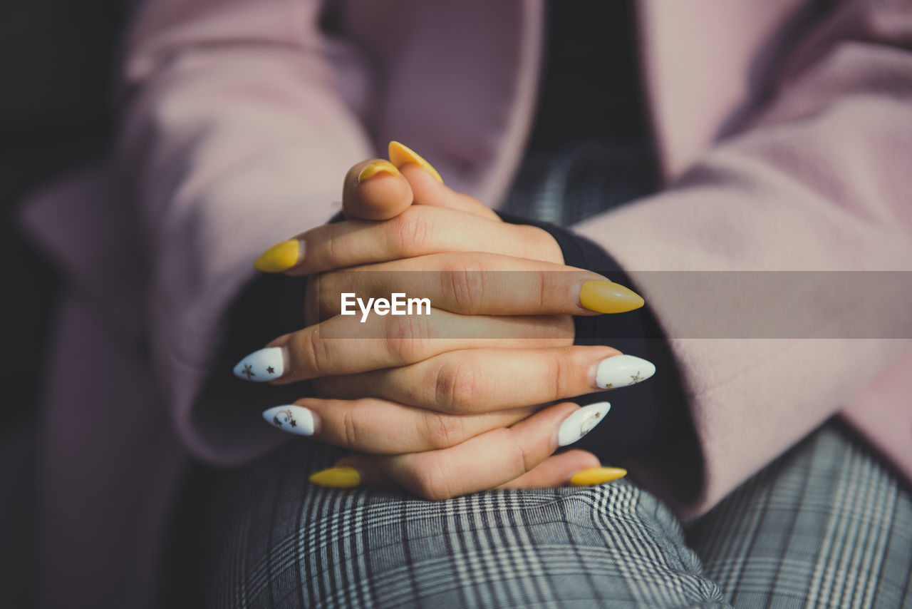 Midsection of woman sitting with hands clasped