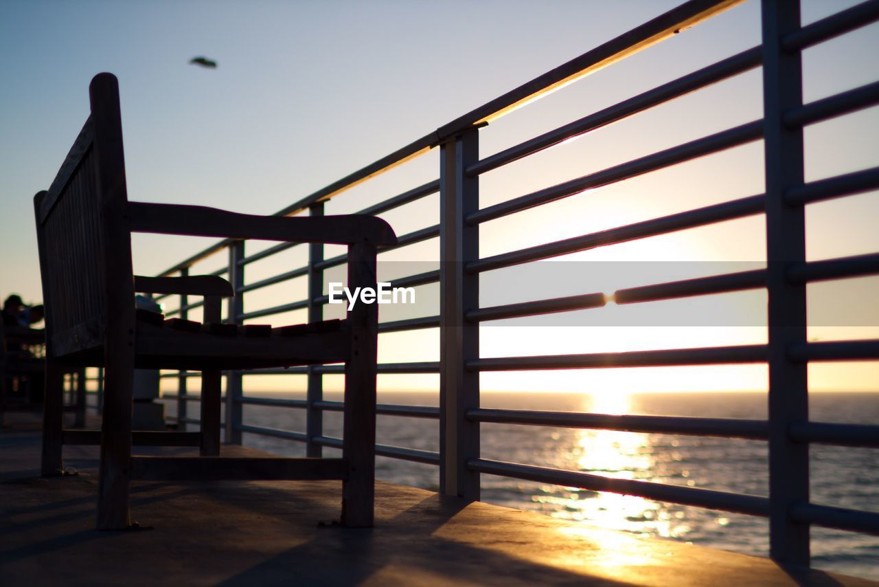 Chairs and terrace railing silhouetted against sunrise