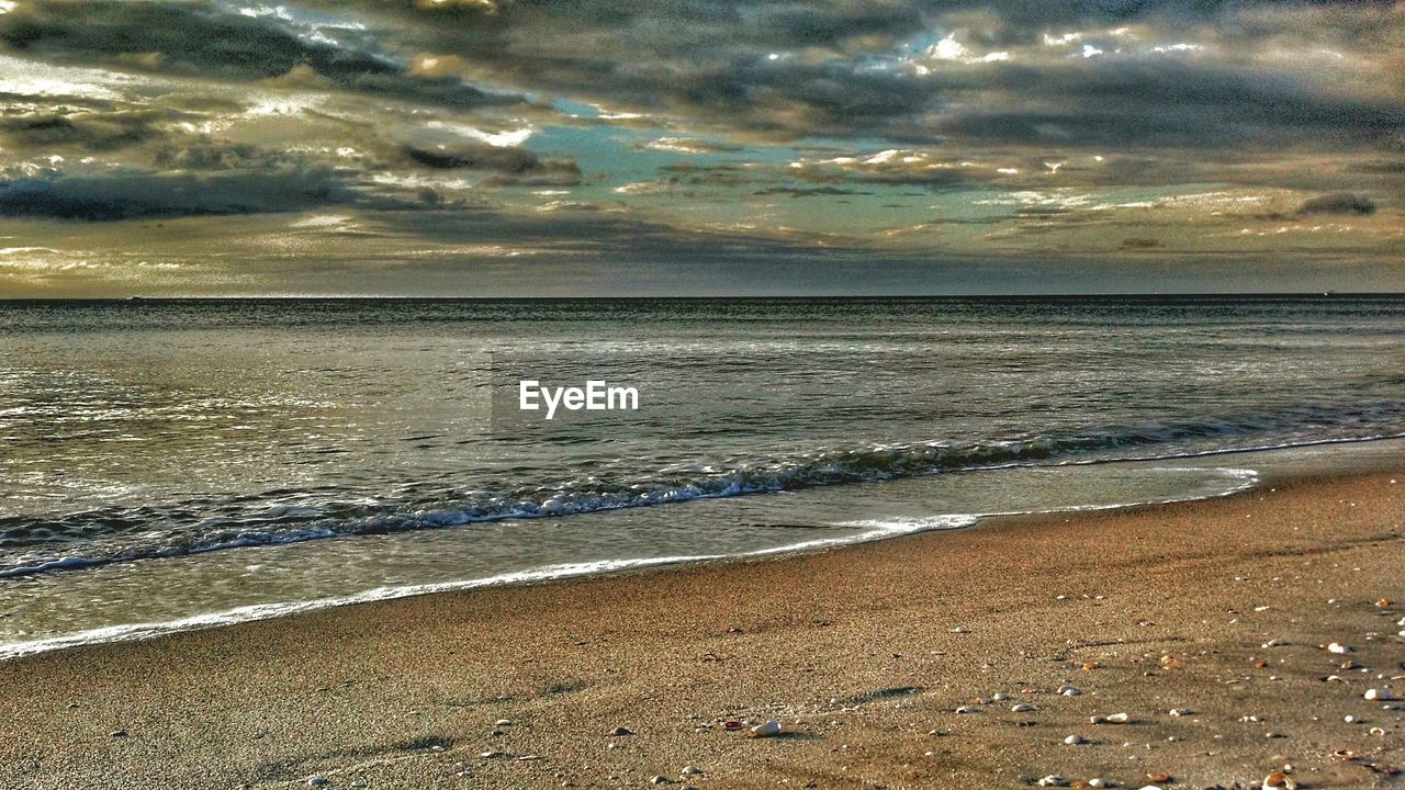 VIEW OF BEACH AGAINST CLOUDY SKY