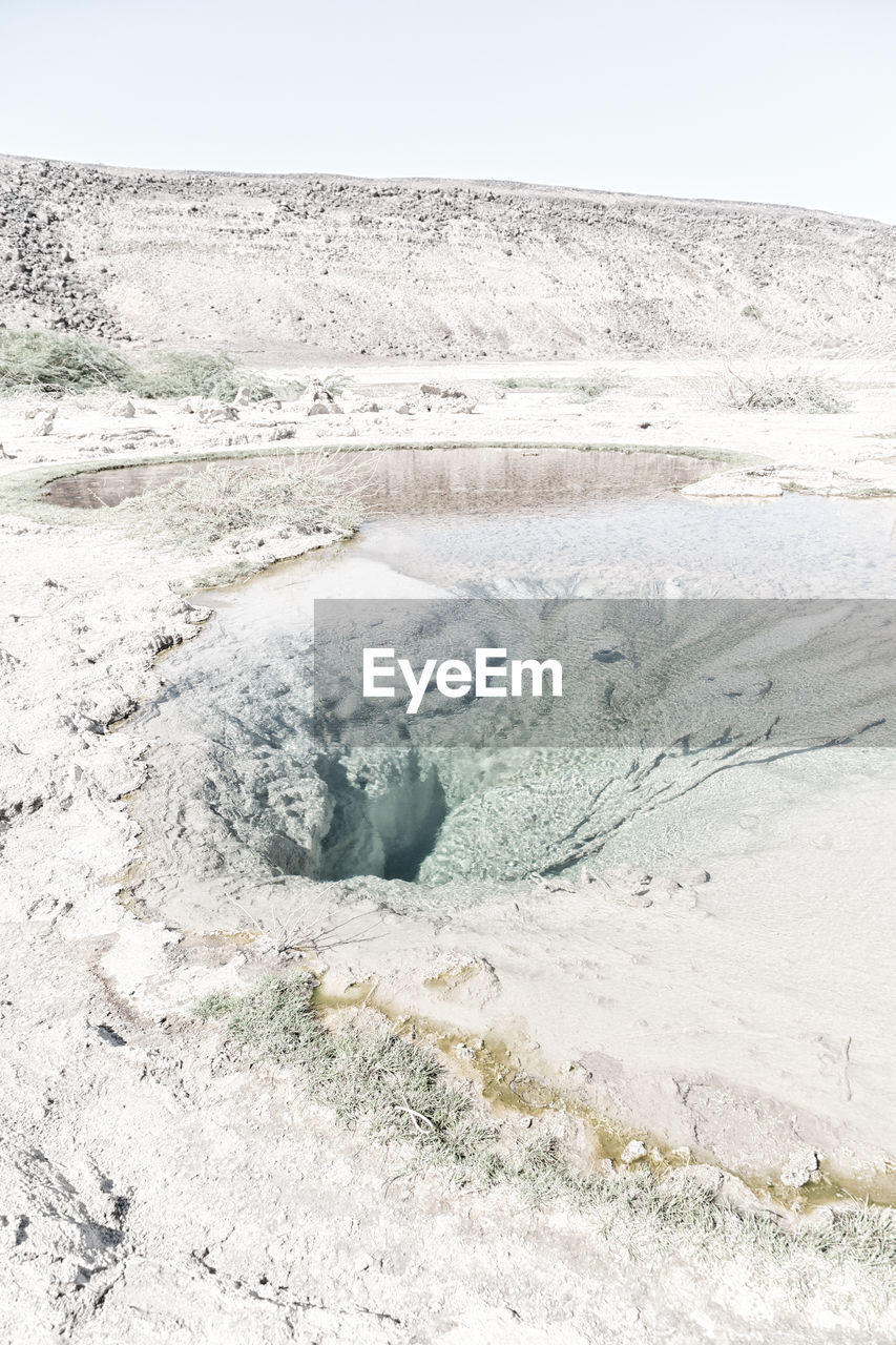 Hot spring in desert against clear sky