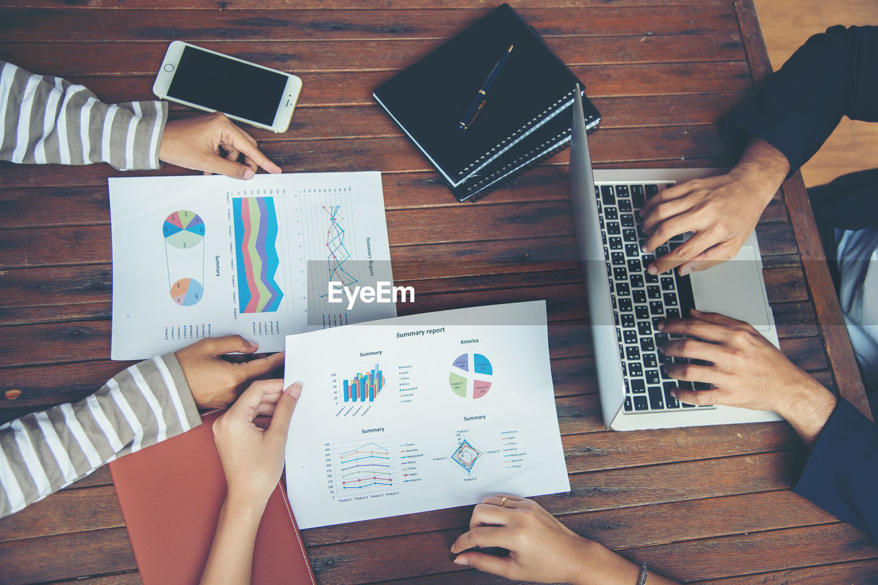 Cropped hands of woman with colleagues holding graph chart